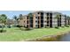 A beautiful tan-colored condo building showcasing manicured lawns and mature palm trees at 6515 Grand Estuary Trl # 208, Bradenton, FL 34212