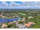 Stunning aerial view of a golf course community featuring a scenic pond, lush greenery, and beautiful homes with tile roofs at 7214 Marlow Pl, University Park, FL 34201