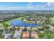 Breathtaking aerial view of a lovely community with a large pond, manicured lawns, tile roofs, and verdant trees at 7214 Marlow Pl, University Park, FL 34201