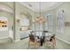 Elegant dining room features a glass table, modern chandelier, and white plantation shutters at 7214 Marlow Pl, University Park, FL 34201