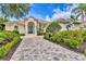 Inviting home featuring a paver driveway, a lush garden, tropical plants, and a decorative green front door at 7214 Marlow Pl, University Park, FL 34201