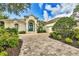 Beautiful home with a long brick driveway, arched entryway with white columns, and professionally landscaped front yard at 7214 Marlow Pl, University Park, FL 34201