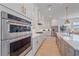 Modern kitchen featuring stainless steel appliances, white cabinets, quartz countertops, and wood flooring at 7279 Kodiak Ln, Sarasota, FL 34240