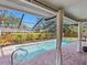 Relaxing pool with screened enclosure, brick deck, and view of fenced yard with tropical landscaping at 7460 Dickens Dr, Sarasota, FL 34231