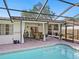 Screened pool area with tile roof, brick paver deck, white privacy curtains, and tropical landscaping at 7460 Dickens Dr, Sarasota, FL 34231