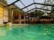 Backyard pool at dusk features screened-in enclosure, privacy curtains, and ambient lighting at 7460 Dickens Dr, Sarasota, FL 34231