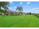 Expansive backyard featuring a lush lawn, tropical landscaping, and a screened-in lanai at 7744 Castleisland Dr, Sarasota, FL 34240