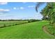 Lush green backyard with a view of a golf course and a privacy fence at 7744 Castleisland Dr, Sarasota, FL 34240
