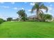 Well-maintained backyard with large grassy area, mature trees, and a screened-in porch at 7744 Castleisland Dr, Sarasota, FL 34240