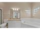 Bright ensuite bathroom with dual sinks, granite counters and jacuzzi tub at 7744 Castleisland Dr, Sarasota, FL 34240