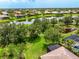 Aerial view highlighting the lush green lawn, screened in porch, trees, and a tranquil lake at 8437 Nandina Dr, Sarasota, FL 34240