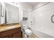 A full bathroom with a tub and shower, toilet, and granite vanity with wooden cabinets at 8437 Nandina Dr, Sarasota, FL 34240