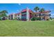 Low angle exterior of a multi-Gathering home with lush green grass, palm trees, and a red roof at 96 Boundary Blvd # 127, Rotonda West, FL 33947