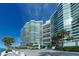 Modern condo exterior with a covered entrance, beautiful landscaping, and blue skies at 988 Blvd Of The Arts # 1016, Sarasota, FL 34236