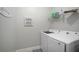 Bright laundry room with modern washer and dryer, storage shelf, and cute decor at 10423 Morning Marsh Ln, Parrish, FL 34219