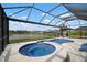 Sparkling screened-in pool and spa overlooking serene lake, offering a perfect backyard retreat at 10423 Morning Marsh Ln, Parrish, FL 34219