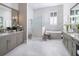 Elegant bathroom with dual vanities, a soaking tub, a glass-enclosed shower, and marble floors at 1198 Blue Shell Loop, Sarasota, FL 34240