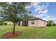 Backyard featuring a well-maintained lawn, complemented by a mature tree and a view of the home's exterior at 12515 Garibaldi Ln, Venice, FL 34293