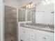 Bathroom featuring a double sink vanity with granite countertops, white cabinetry, and glass enclosed shower at 12515 Garibaldi Ln, Venice, FL 34293