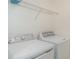 Functional laundry room with a full-sized washer and dryer, as well as shelving for storage at 12515 Garibaldi Ln, Venice, FL 34293