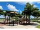Community playground featuring modern play equipment, shaded benches, and mature trees at 12515 Garibaldi Ln, Venice, FL 34293