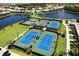 View of immaculately maintained tennis courts with picturesque pond views and surrounding residences at 12515 Garibaldi Ln, Venice, FL 34293