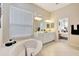 Bright bathroom featuring a soaking tub, double vanity, and doorway to the bedroom at 12710 Stone Ridge Pl, Lakewood Ranch, FL 34202