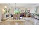 Open-concept living and dining area with a fireplace, modern chandelier, and views of lush landscaping at 12710 Stone Ridge Pl, Lakewood Ranch, FL 34202
