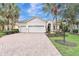 Inviting single-story home with a well-manicured lawn and brick driveway leading to a spacious three-car garage at 12710 Stone Ridge Pl, Lakewood Ranch, FL 34202