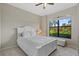 Bedroom features a white bed with pillows, large window with view of the tropical landscaping at 14216 Florida Rosemary Dr, Bradenton, FL 34211