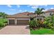 Charming home with a tile roof, a three-car garage, a brick paver driveway, and lush landscaping at 14216 Florida Rosemary Dr, Bradenton, FL 34211