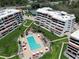 An aerial view of condos, swimming pool, and tennis courts surrounded by lush landscaping and meticulously maintained lawns at 1445 Gulf Of Mexico Dr # 203, Longboat Key, FL 34228