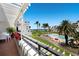 Scenic balcony view showcasing the pool, beach, and lush landscaping of the community, with patio furniture on the red-tiled floor at 1445 Gulf Of Mexico Dr # 203, Longboat Key, FL 34228