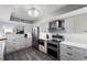 Modern kitchen with white cabinets, stainless steel appliances, a decorative backsplash, and wood-look flooring at 1445 Gulf Of Mexico Dr # 203, Longboat Key, FL 34228