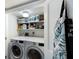 Convenient laundry area with modern washer, dryer, and storage shelving at 1445 Gulf Of Mexico Dr # 203, Longboat Key, FL 34228