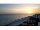 A breathtaking sunset over the ocean, showcasing a serene beach with a coastal building and a sandy shoreline at 1445 Gulf Of Mexico Dr # 203, Longboat Key, FL 34228