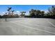 A full tennis court on a sunny day showcases a meticulously maintained surface and surrounding trees for a luxurious play experience at 1445 Gulf Of Mexico Dr # 203, Longboat Key, FL 34228