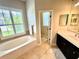 Bright bathroom featuring a soaking tub under a window and a vanity with dark cabinets at 1539 Ormond Ter, Parrish, FL 34219