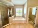 Beautiful bathroom featuring a soaking tub, glass enclosed shower, and large windows for natural light at 1539 Ormond Ter, Parrish, FL 34219