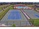 Aerial view of the tennis and basketball courts with a pool and clubhouse in the background at 18620 Cortes Creek Blvd, Spring Hill, FL 34610