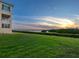 Lush backyard view of the sunset with green lawn and manicured bushes by the water at 2424 Placida Rd # D102, Englewood, FL 34224