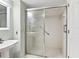 Bathroom featuring a white-tiled walk-in shower with glass doors and grab bars for safety at 2424 Placida Rd # D102, Englewood, FL 34224