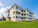 Exterior view of the condo building featuring multiple balconies, blue awnings, and a well-kept lawn at 2424 Placida Rd # D102, Englewood, FL 34224