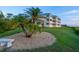 Exterior shot of property showcasing mature palm trees, lush lawn, and building details at 2424 Placida Rd # D102, Englewood, FL 34224