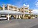 Covered parking area with multiple parking spaces beneath condo building and lush landscaping at 2424 Placida Rd # D102, Englewood, FL 34224