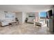 Bright living room with travertine floors, fireplace, ocean view, and white furniture at 2425 Gulf Of Mexico Dr # 14B, Longboat Key, FL 34228