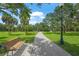 Picturesque walking path through the community with mature trees, a decorative lamppost, and a distant view of a fountain at 2524 Tuttle Way, Sarasota, FL 34239