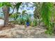 Serene backyard featuring a gravel area with colorful chairs, lush foliage and a glimpse of the charming home at 315 Magnolia Ave, Anna Maria, FL 34216