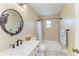 Cozy bathroom featuring a shower-tub combination, decorative tile work, and a large round mirror with decorative accents at 315 Magnolia Ave, Anna Maria, FL 34216