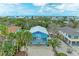 Charming blue beach house featuring a spacious front porch and lush tropical landscaping at 315 Magnolia Ave, Anna Maria, FL 34216